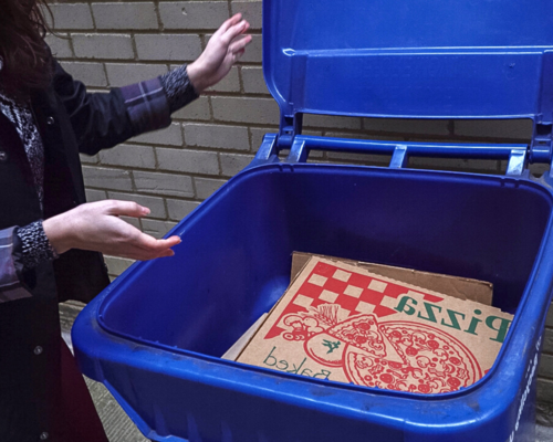 一个女人盖上了回收箱里的披萨盒